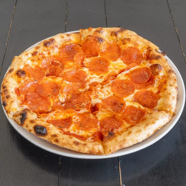 A whole pepperoni pizza with a crispy crust and melted cheese on a white plate.